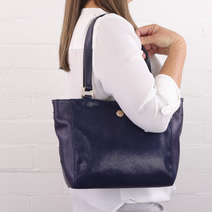 lady wearing navy blue leather and suede tote handbag on shoulder#colour_navy-cosmos