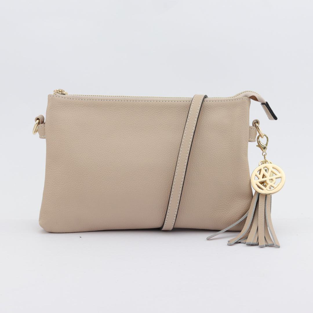 neutral nude coloured pebbled leather handbag with adjustable leather cross body strap and removable logo charm with gold hardware#colour_nude