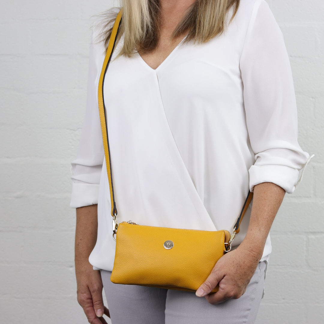 woman wearing yellow saffron coloured pebbled leather handbag across the body#colour_saffron