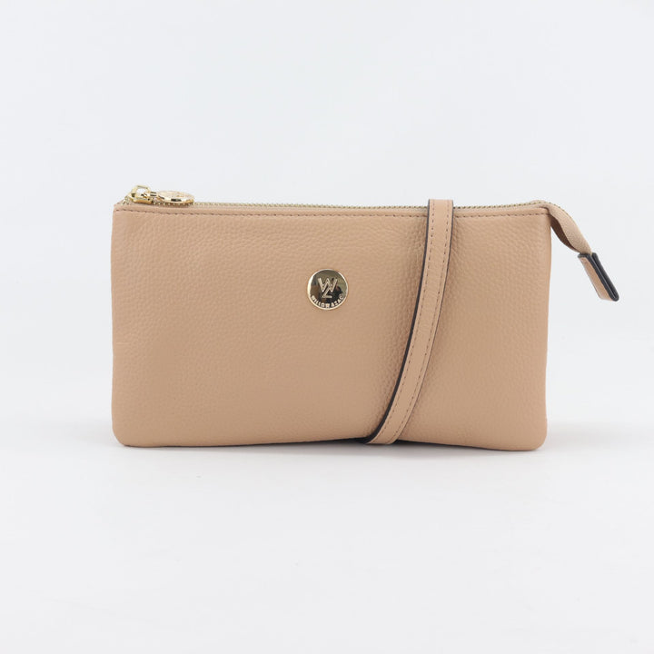 studio image of evie clutch handbag in blush pink standstone coloured pebbled leatehr with long crossbody strap and gold button logo#colour_sandstone