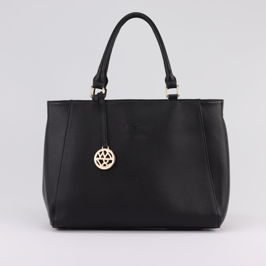 front view of black leather tote handbag with gold badge charm and stamped logo#colour_black