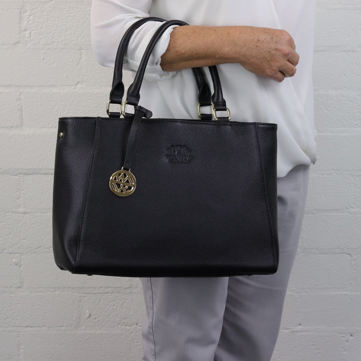 woman wearing black tote workbag on forearm