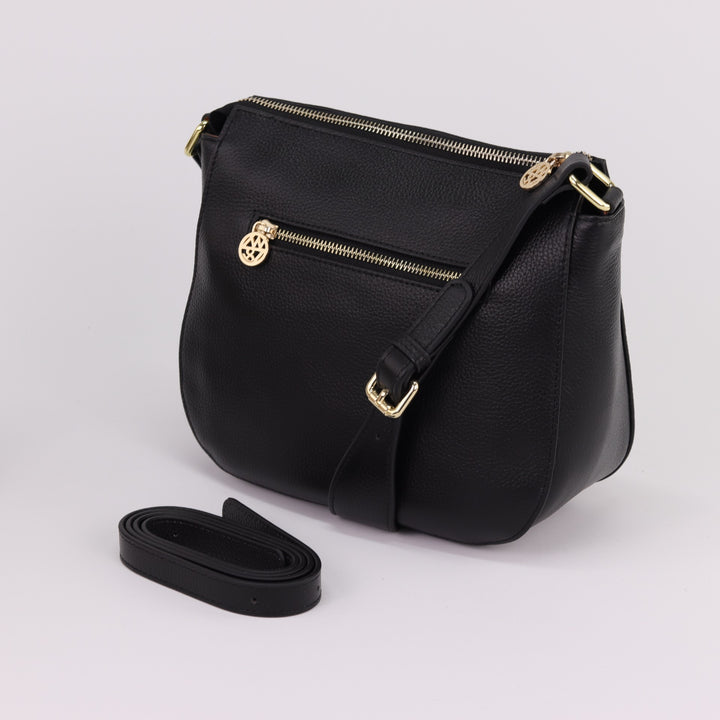 rear and side view of curved shaped leather tote with gold buckles on strap and rear zipper#colour_black