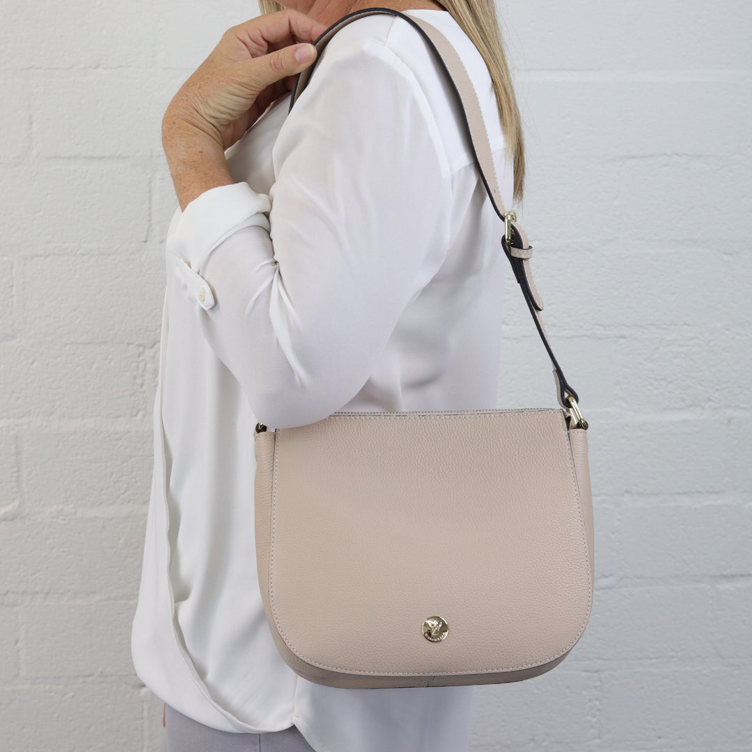lady model wearing nude coloured leather bag with short strap on shoulder#colour_nude