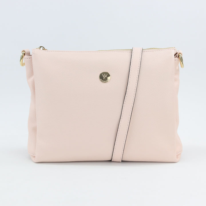 light soft pink leather handbag wrapped with adjustable long leather strap and small button logo#colour_pink-whisper
