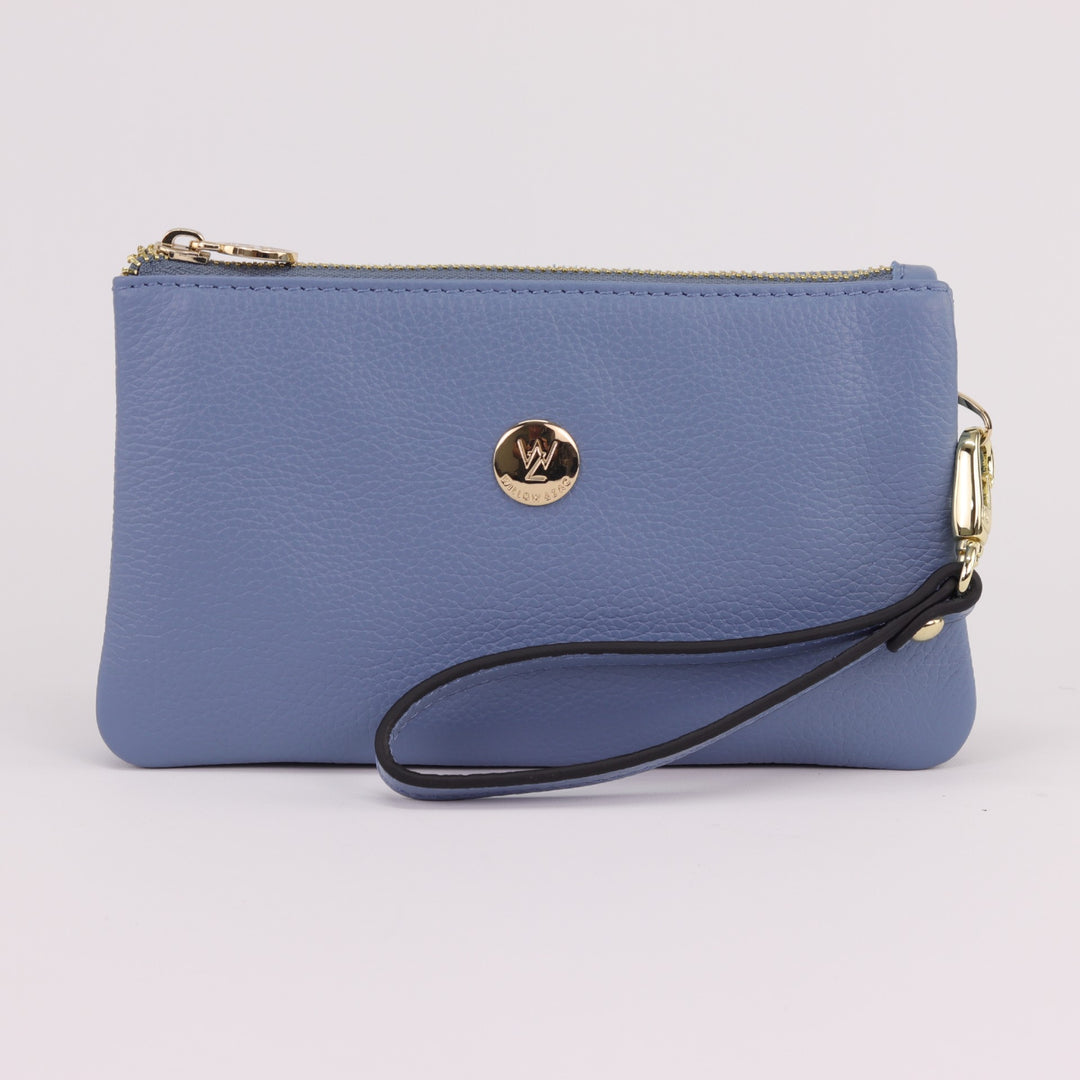 sky blue coloured purse clutch with removable wrist strap and gold button logo with zip closure#colour_serene-blue