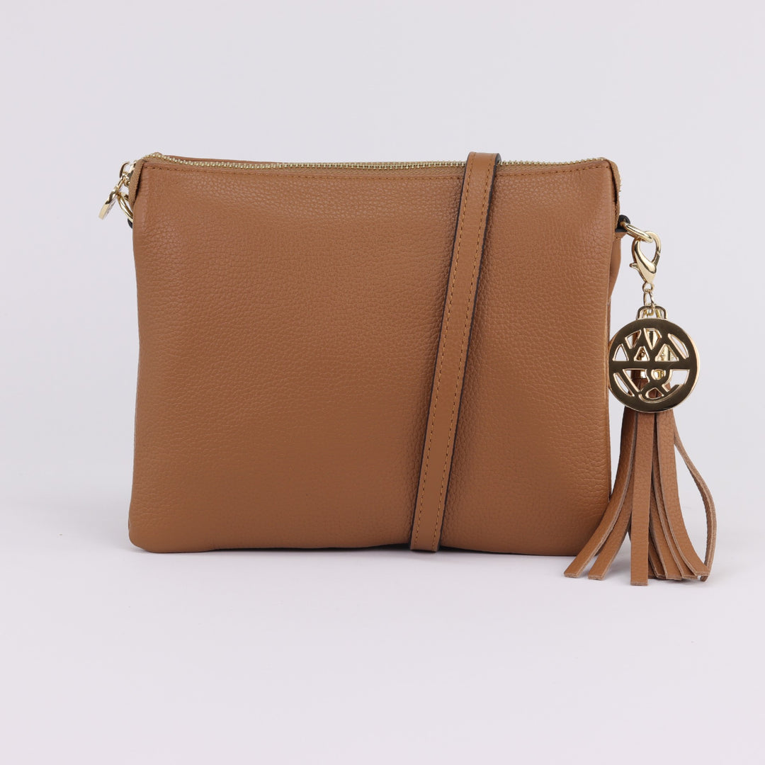 brown tan leather handbag with long crossbody strap and optional tassel with gold logo charm and zips#colour_caramel